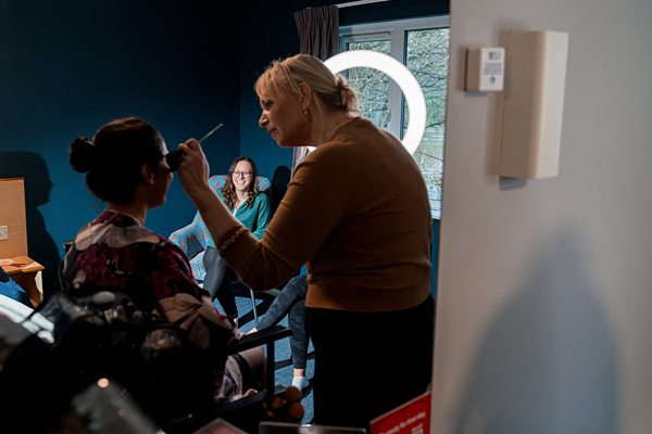 Makeup artist working with client indoors.