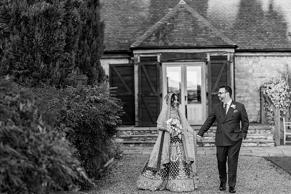 Couple in wedding attire holding hands outdoors.