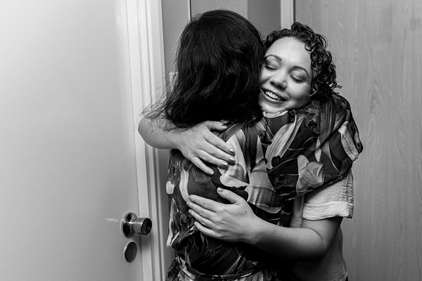 Two women embracing happily in black and white photo.