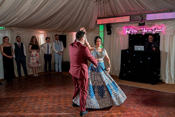 Couple dancing at wedding reception with guests watching.
