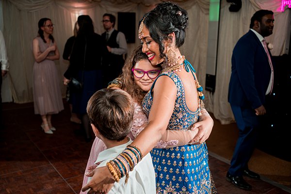 Woman in traditional attire embraces children at event.