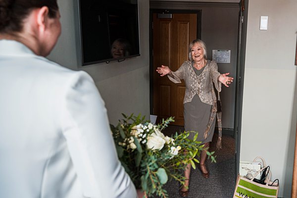 Woman greeting with open arms, man holding flowers blurred.