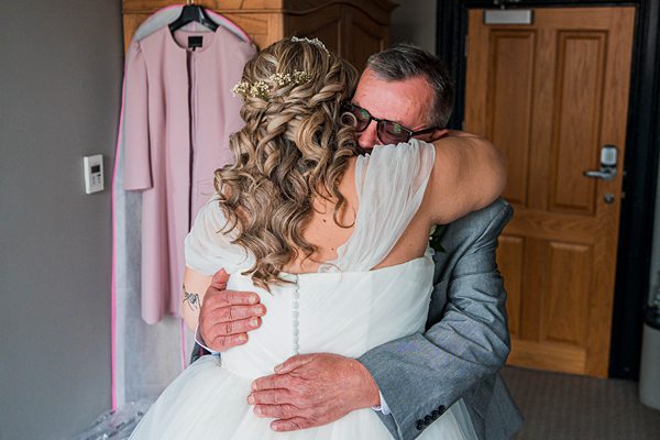 Bride embracing man in suit before wedding ceremony.