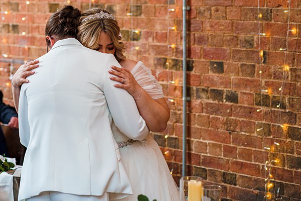 Bride and groom embracing at wedding with fairy lights.