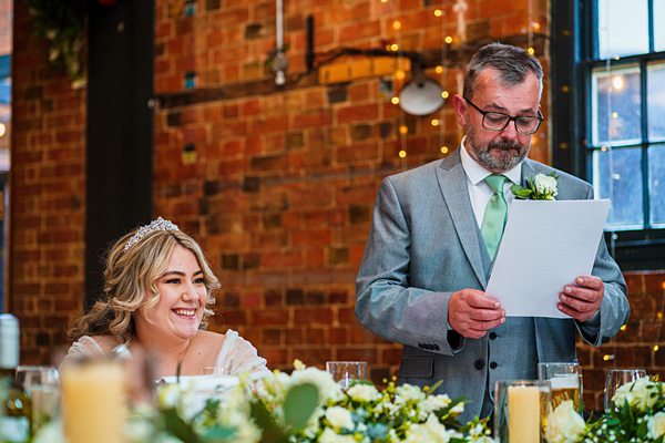 Father giving speech at daughter's wedding reception.