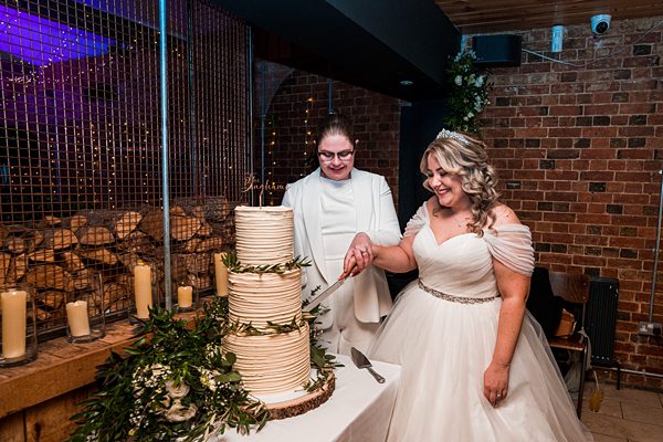 Bride cutting cake with guest at wedding reception.