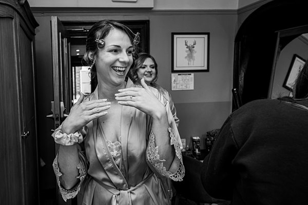 Bride in silk robe laughing during wedding preparations.