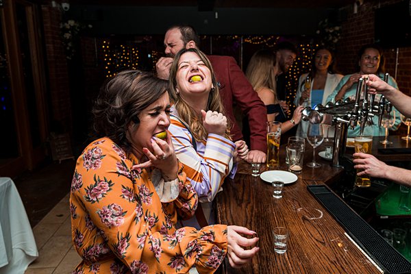 People laughing at bar party with festive lights.