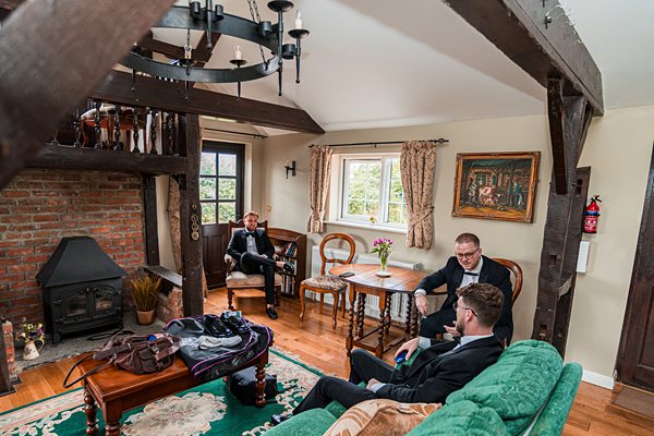 Three men relaxing in cozy, rustic living room.