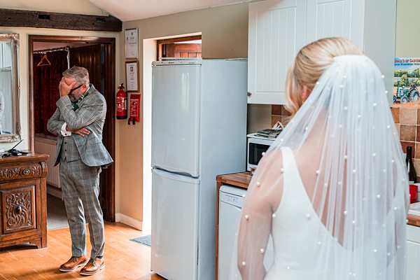 Bride in veil, emotional man in kitchen.