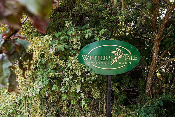 Winter's Tale Country Barn sign among greenery