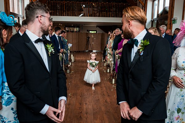 Flower girl walking down aisle at wedding ceremony.