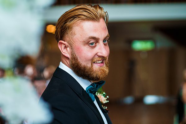 Smiling groom in a black tuxedo at wedding.