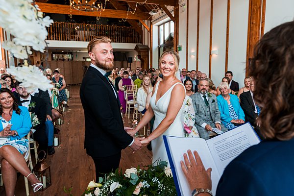 Couple exchange vows at rustic wedding ceremony.
