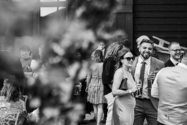 Outdoor wedding reception with smiling guests in formal attire.