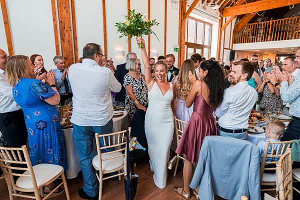 Joyful wedding reception with clapping guests and happy couple.