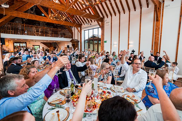 Guests toasting at a lively wedding reception.