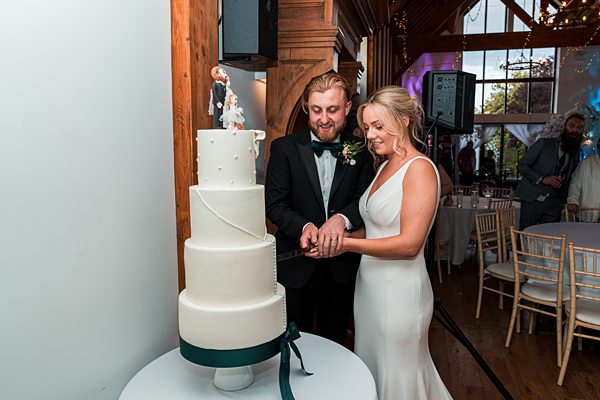 Bride and groom cutting wedding cake together.