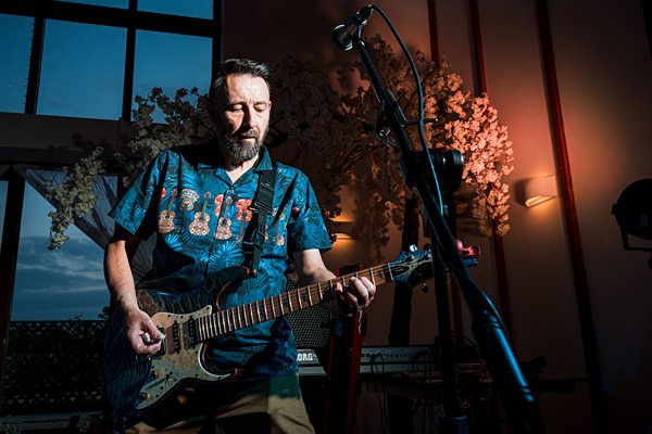 Musician playing electric guitar on stage.