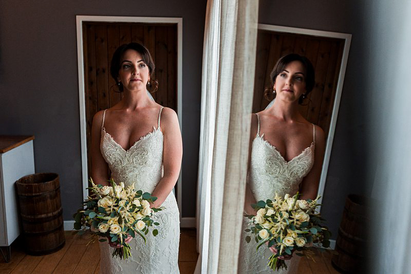 Bride with bouquet reflected in mirror.