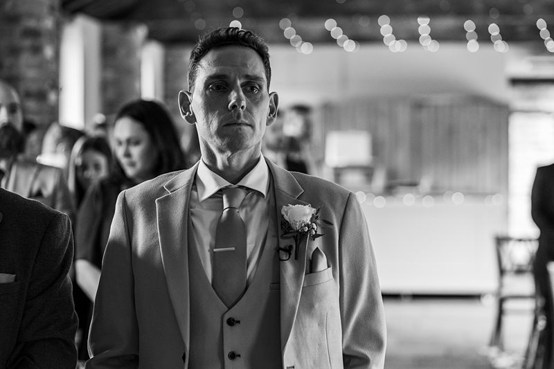 Groom in suit at wedding ceremony, black and white photo.