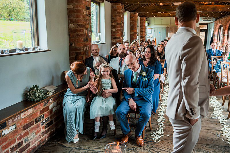 Wedding ceremony scene with guests and bride entering.