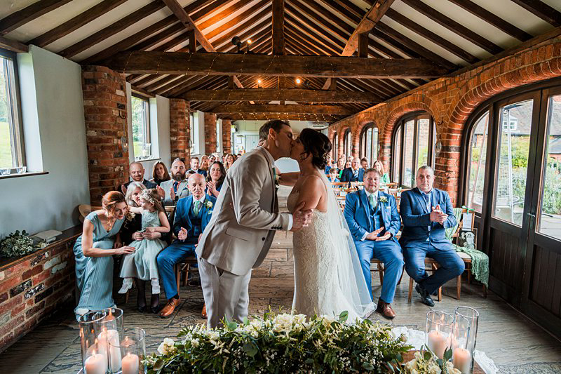 Couple kissing at rustic wedding ceremony.