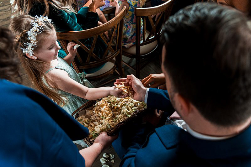 Child giving flower petals at wedding ceremony.