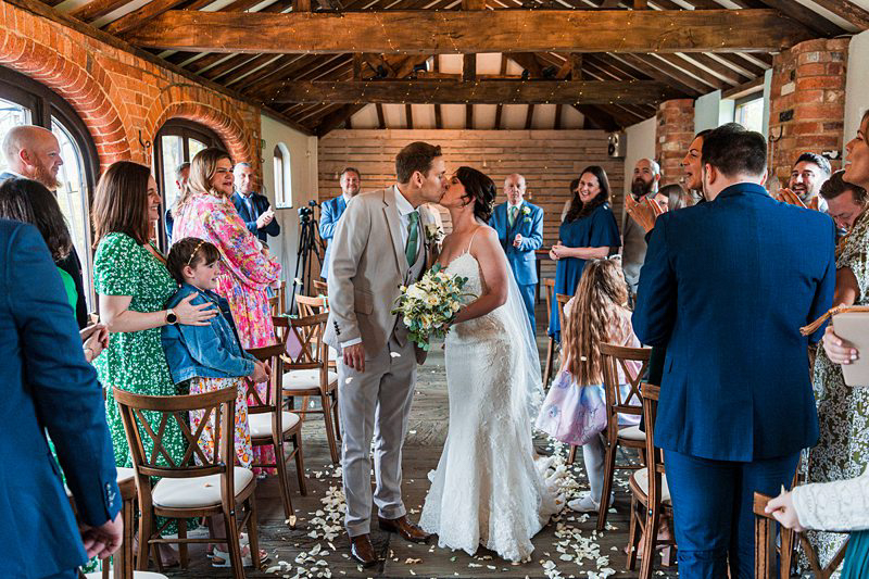 Bride and groom kissing at wedding ceremony.