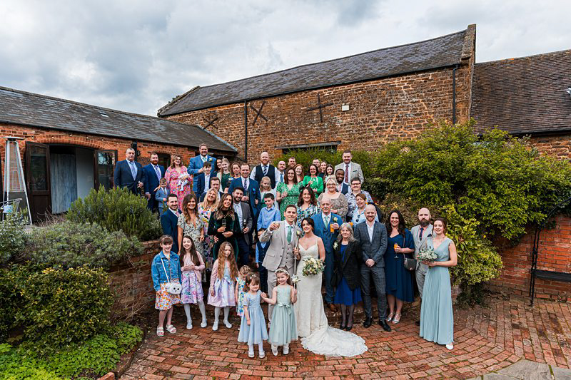 Group wedding photo outside brick venue.