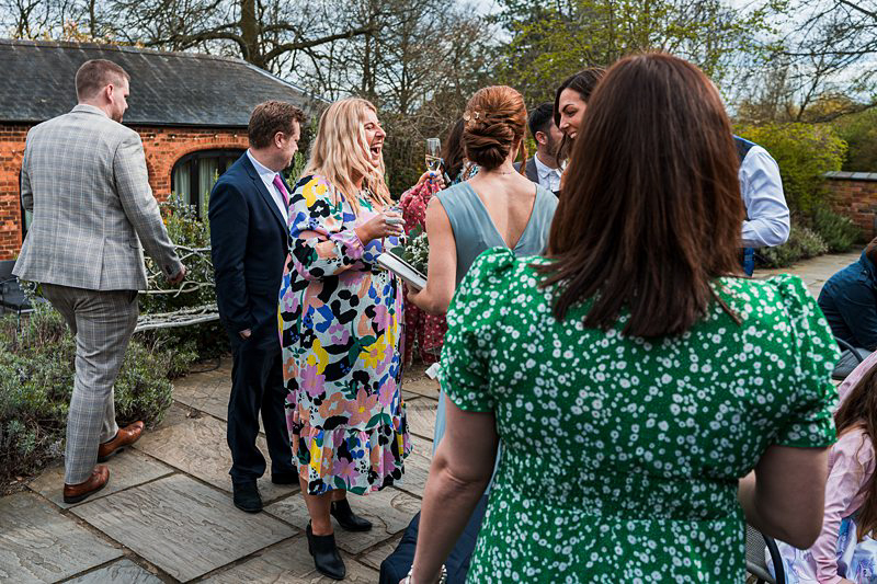 Outdoor garden party with guests chatting and laughing.