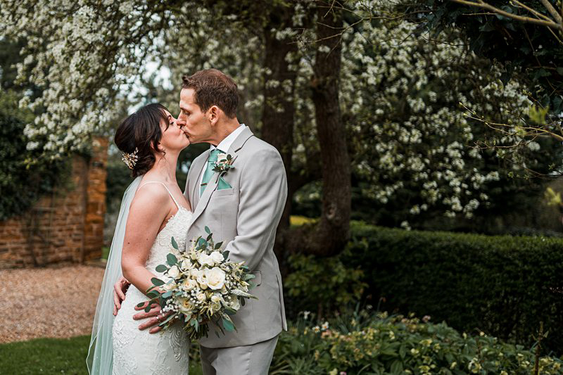 Bride and groom kissing in garden wedding.