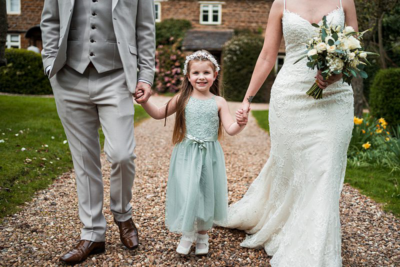 Bride, groom, flower girl walking hand in hand.