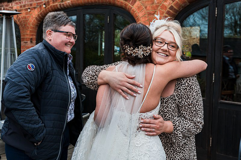 Joyful wedding embrace outside brick building.