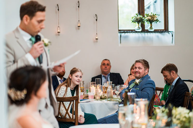 Wedding speech moment with attentive guests at reception.