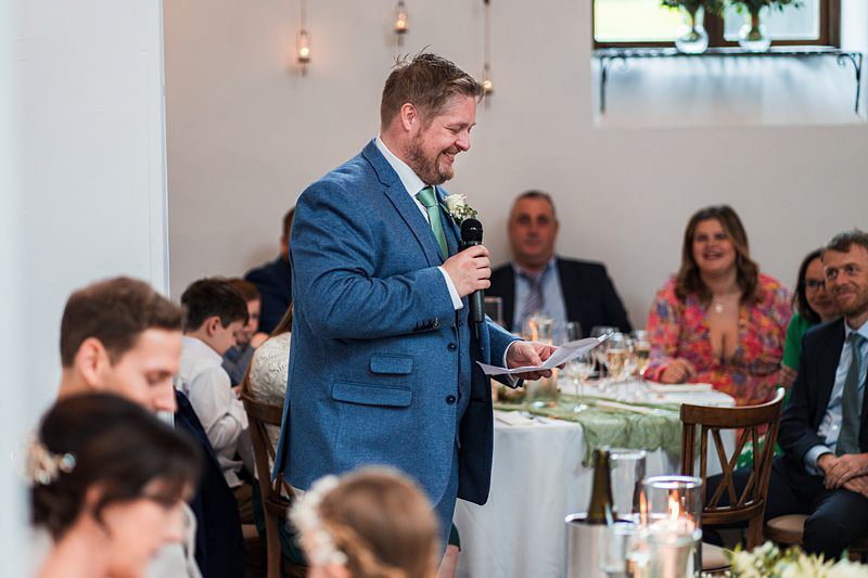 Man giving speech at wedding reception.
