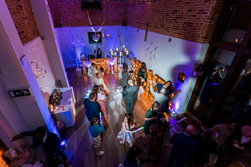 Wedding dance floor with guests and blue lighting.