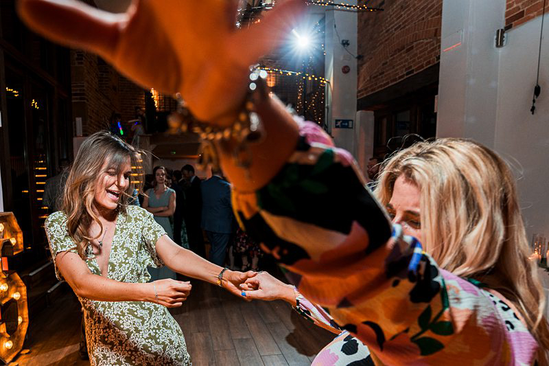 Women dancing happily at indoor party.