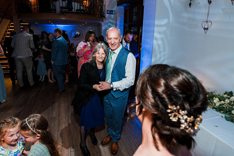 Couple dancing at festive event with guests.