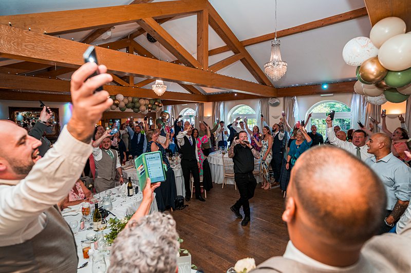 Guests cheering at wedding reception in decorated hall.