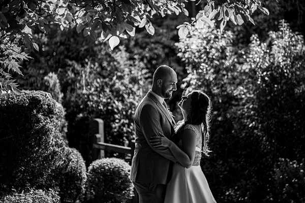 Couple embracing in garden, black and white wedding photo.