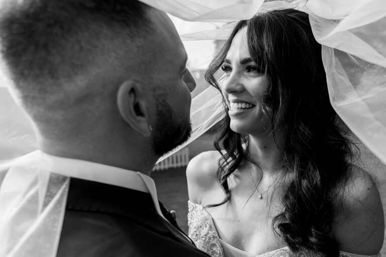 Couple sharing intimate moment under bridal veil.