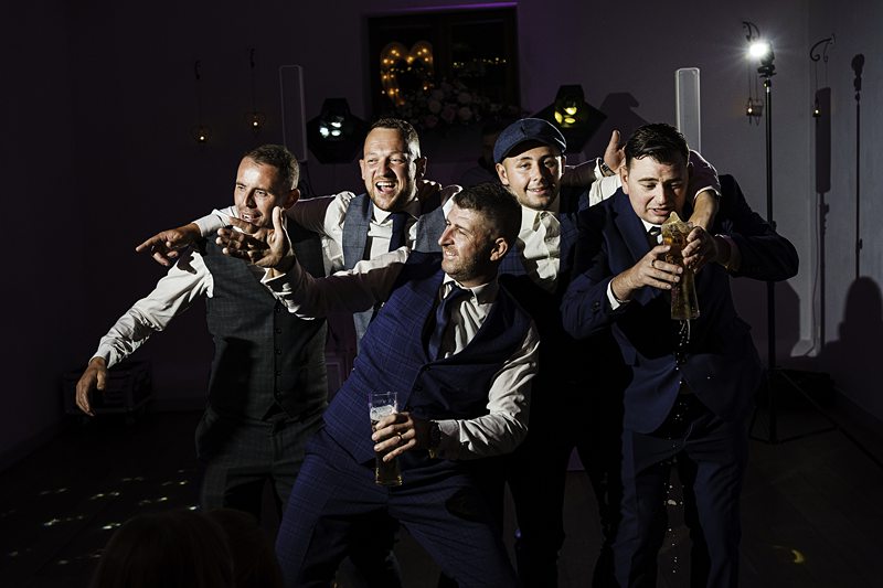 Men posing and having fun at a wedding party.