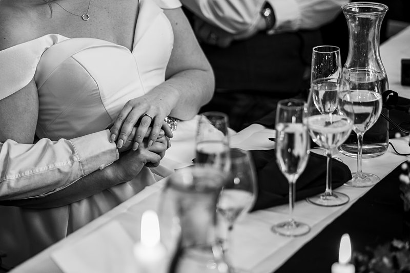Couple holding hands at wedding table.