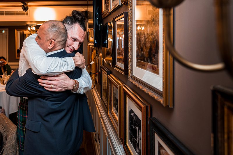 Two men hugging emotionally at an event.
