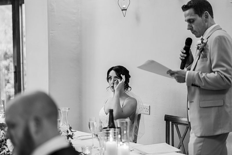 Emotional bride at wedding reception during speech.