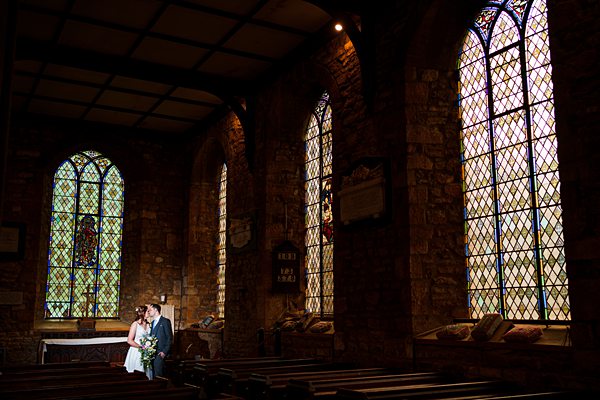 Couple embracing in historic church with stained glass windows.