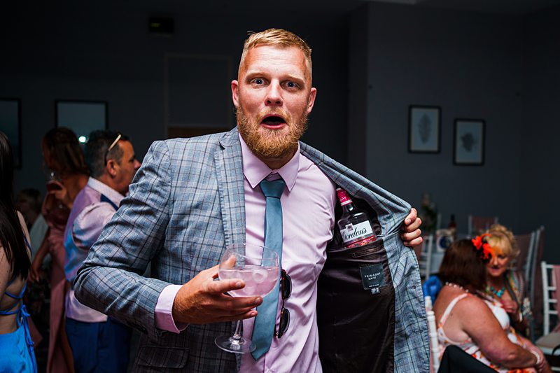 Man with drink looks surprised at party.
