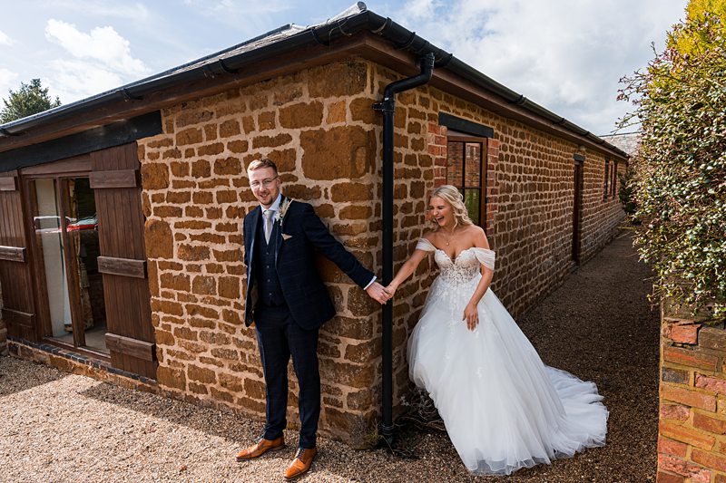 Bride and groom holding hands outside stone building