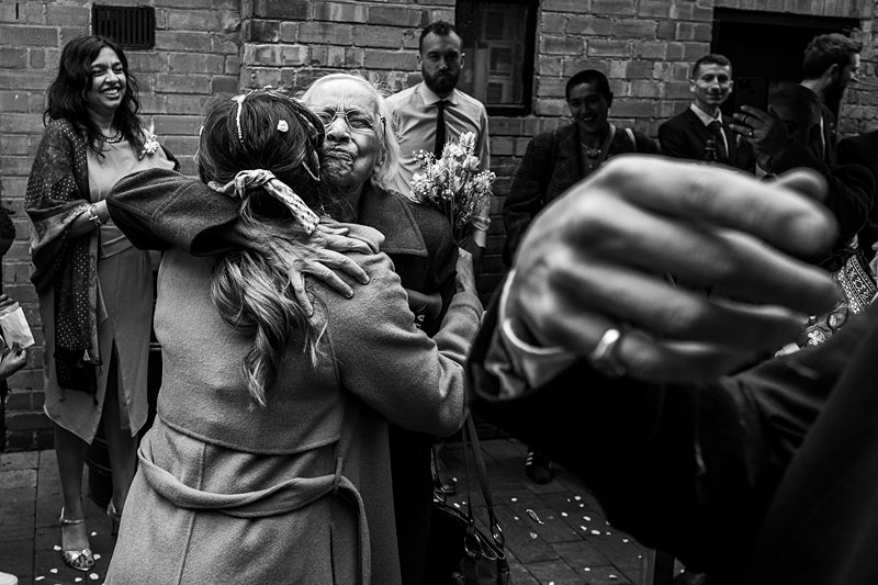 Emotional embrace at wedding celebration with onlookers smiling.